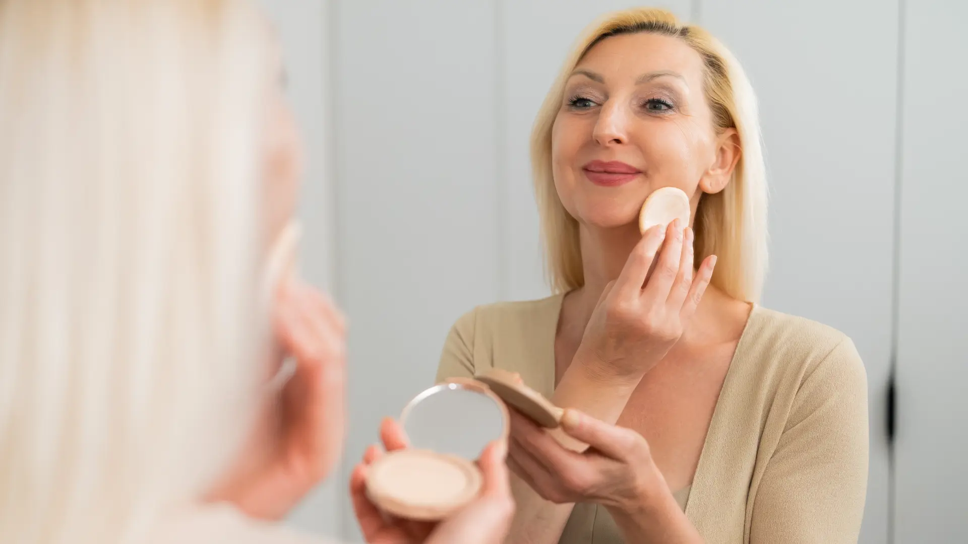 shutterstock_2667409425 ogledalo puder šminka šminkanje plavuša sređivanje lice bore make up-6a44bfee82f9d.webp